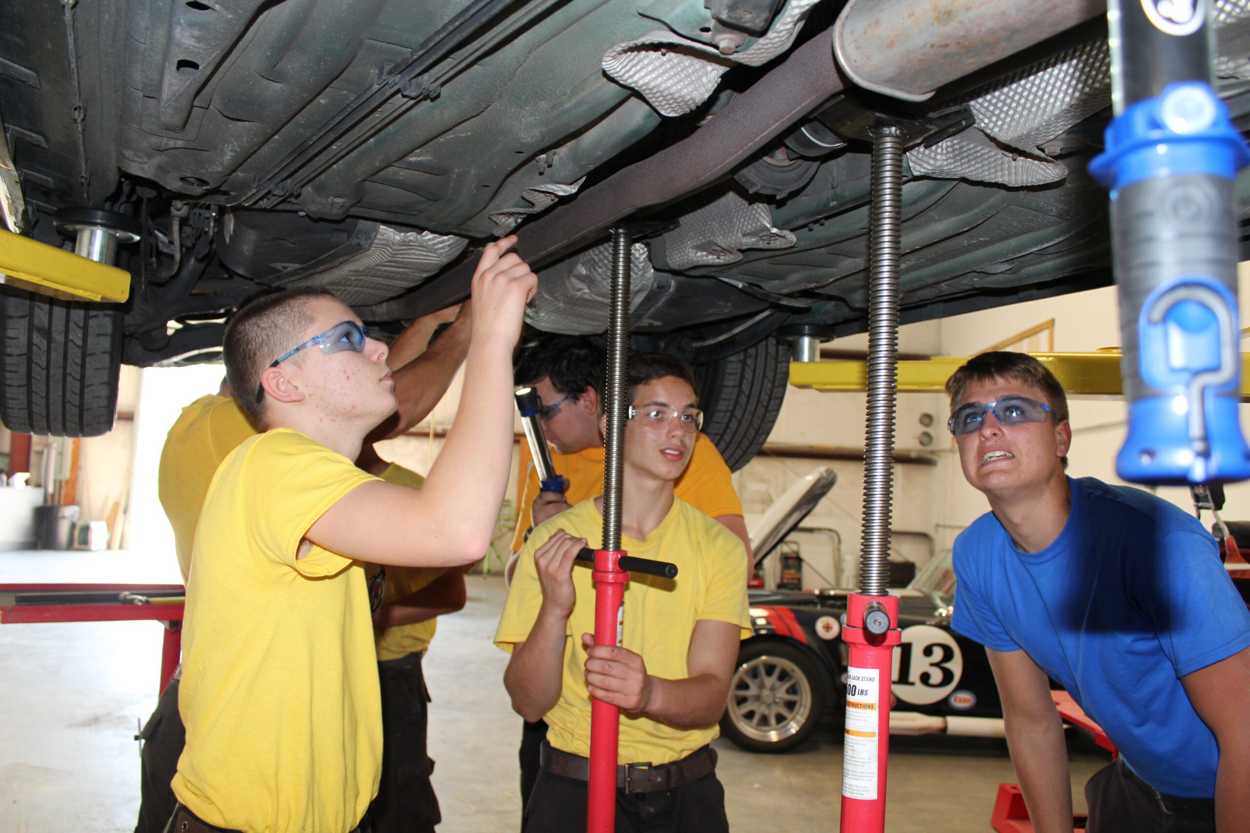Group Of Male Students Fixing A Car